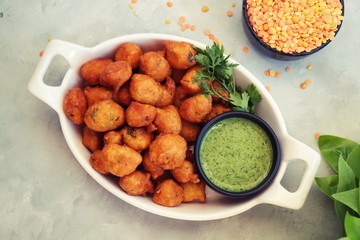 Moong dal ke pakode, ram laddoo, bhajias, Moongode or fritters. served with green mint and coriander chutney. Served over light background. Selective focus. with copy space.