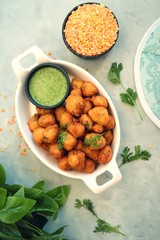 Moong dal ke pakode, ram laddoo, bhajias, Moongode or fritters. served with green mint and coriander chutney. Served over light background. Selective focus. with copy space.