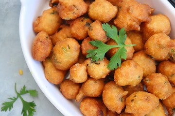 Moong dal ke pakode, ram laddoo, bhajias, Moongode or fritters. served with green mint and coriander chutney. Served over light background. Selective focus. with copy space.