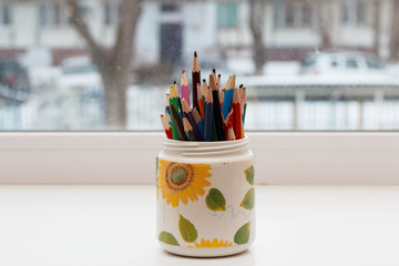 colored pencils in a glass on the windowsill in kindergarten