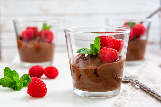 Chocolate nutella mousse dessert with raspberries and mint served in a glass, selective focus 