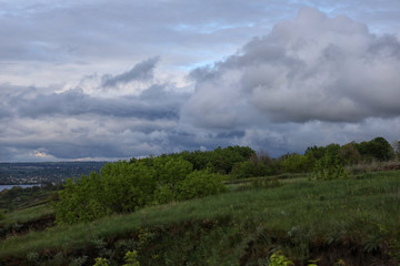 dramatic sky with clouds. green fiels and blue sky