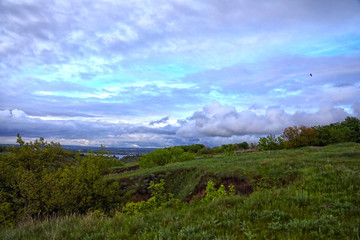 dramatic sky with clouds. green fiels and blue sky