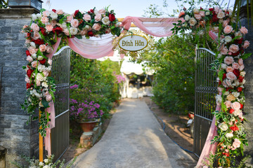 The engagement gate in western Vietnam is decorated with many pink flowers and chiffon fabric, traditional wedding