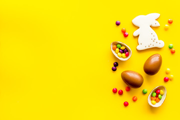 Easter sweets frame. Chocolate eggs and bunny gingerbread on yellow background top-down frame copy space