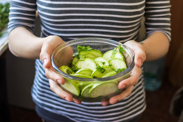 Green fresh zucchini slices salad. Vegan, vegetarian healthy food. Woman hands hold salad bowl.