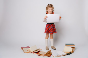 child girl schoolgirl in school uniform holding a blank sheet of paper on a white background