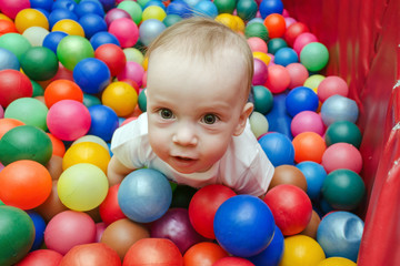 Fototapeta na wymiar little boy plays with colorful balls in the playroom