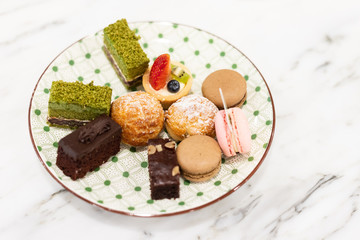 Small chocolate and Green tea Strawberry cakes on dish. Sweet paradise.