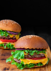 Two fresh hamburger on a wooden table. Closeup. Shallow depth of field.