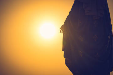 Silhouettes of the blessed Virgin Mary statue figure in a warm tone - sunset scene. Catholic...