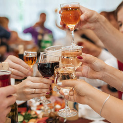 hands of a group of friends clinking glasses of wine and toasting