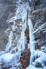 Fototapeta na wymiar Frozen waterfall in winter. Icicles on the rock.