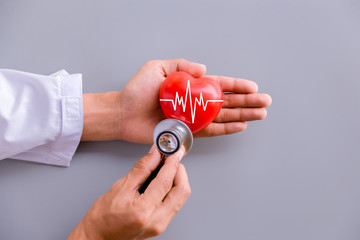 Doctor hands holding red heart with ecg line and stethoscope - obrazy, fototapety, plakaty