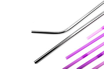 Reusable metal straws - stainless steel, an environmentally friendly set of drinking straws. Metal straws on a white background, complement the composition of disposable purple straws.