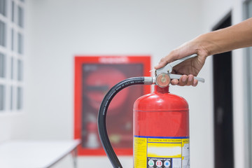 Naklejka premium Technician checking red fire extinguishers available in fire emergencies,safety concept.