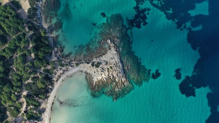 Aerial view of Vourvourou beach, small peninsula in turquoise water of Aegean sea. Waves beating cliff rocky coastline. Halkidiki, Greece.