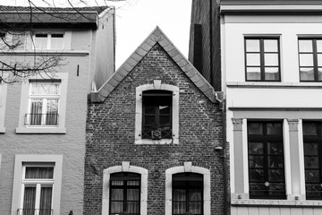 old european house crammed between two newer buildings in black and white