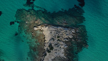 Fototapeta na wymiar Aerial view of Vourvourou beach, small peninsula in turquoise water of Aegean sea. Waves beating cliff rocky coastline. Halkidiki, Greece.