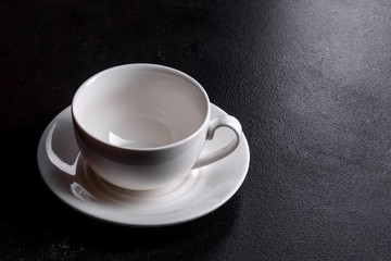 Preparation of aromatic morning coffee. Empty white coffee cup on a dark table