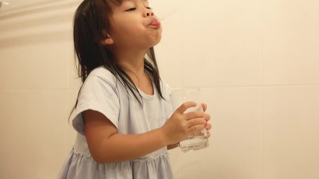 Happy little child girl brushing teeth and clean oral with water in the bathroom. Oral hygiene concept.