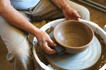 Fototapeta na wymiar Professional potter working at kick wheel in home studio. Handmade mastery concept. Artisan at workshop.