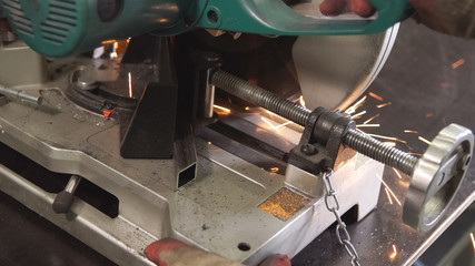 Grinding in steel manufactory. Working man with big saw cutting metal. Dangerous and hard work concept.