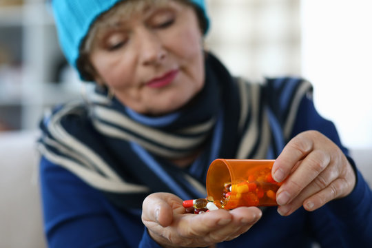 Elderly woman puts capsules from can in palm. Undesirable effects drugs. Use drug in therapeutic doses. Danger to elderly person. Serious chronic diseases frequent companion aging