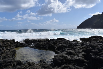 Fototapeta na wymiar Waves crashing on a lava rock beach in Hawaii