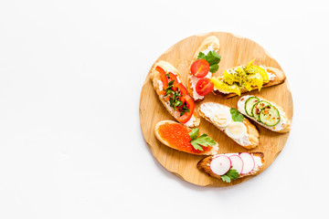 Set of bruschetta on cutting board on white background top-down copy space