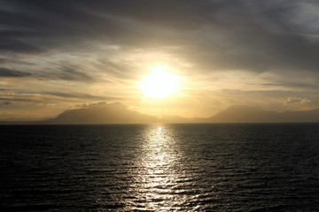 evocative image of sunset over the sea with headland silhouette in the background