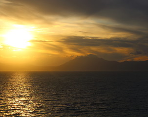 evocative image of sunset over the sea with headland silhouette in the background