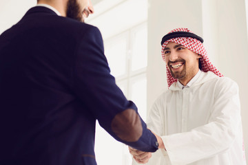 Handshake of arabic and european businesspeople in office.