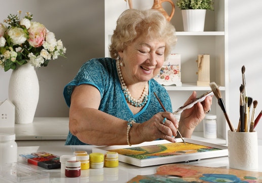 Adult senior woman paints a picture in her studio