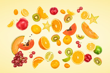 Flying Fruits healthy food summer color background. Papaya, orange, apple, kiwi, melon. Colorful levitation, falling fly fruit creative vitamin concept. Fresh tropical fruit on yellow