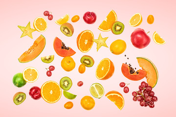 Flying Fruits healthy food summer color background. Papaya, orange, apple, kiwi, melon. Colorful levitation, falling fly fruit creative vitamin concept. Fresh tropical fruit on pink