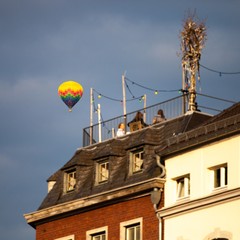 Fototapeta na wymiar hot air balloon floating over people on roof top