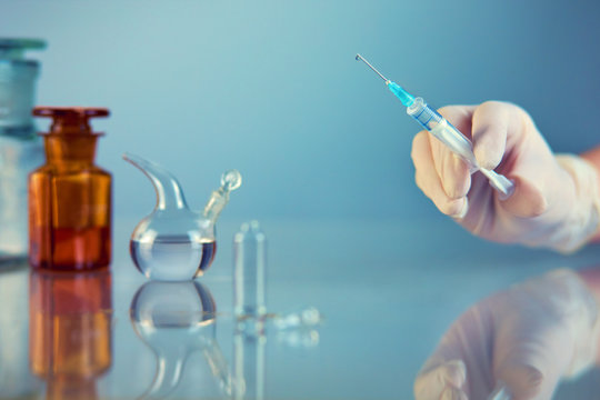 Doctor holds a syringe with medicine. on the background of medical supplies, blue background