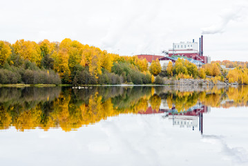 Factory with a smokestack reflected on a still river