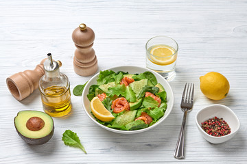 Salmon salad, cucumber, spinach, lollo, lettuce. Home made vegetarian salmon salad. Seafood tasty diet concept. Mix leaves greens with salmon fish in plate on white wood background.