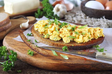 Scrambled eggs on slice of fried rye bread, parsley and green onion dressing