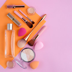 Naklejka premium Makeup brushes and decorative cosmetics on color background, with empty space for text. Top view