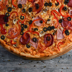 Flat lay photograph of tasty italian pizza on rustic wood. Pepperoni, cheese and peppers. Delicious food.