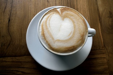 Taza de café con leche con corazón en mesa de madera 