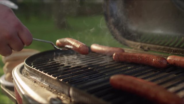 Close-up of delicious hot dogs cooking on the grill in slow motion