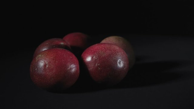 Video of rotating exotic passion fruit on black background