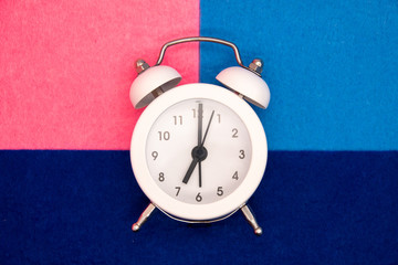 Retro alarm clock on the blue and pink background