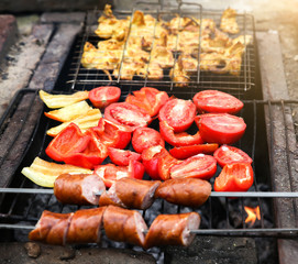 Barbecue on the open fire. Sweet pepper and tomatoes. Chicken and sausages frying.