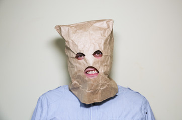 Kraft paper bag is on the man's head. Holes for eyes. Funny idea. Guy is angry.