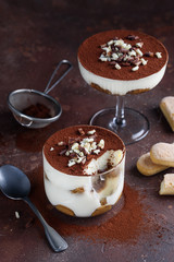 Tiramisu traditional italian dessert in glasses on brown background. Selective focus